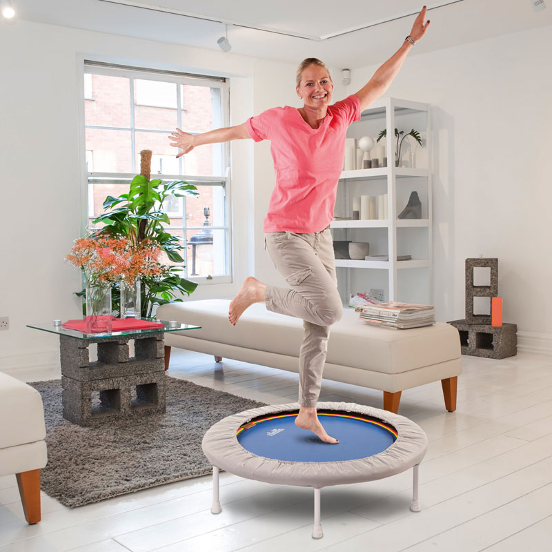 Frau springt im Wohnzimmer auf einem Trimilin Minitrampolin